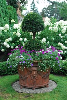 a potted planter filled with purple and white flowers in the middle of a garden