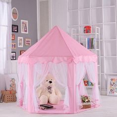 a teddy bear sitting in front of a pink tent