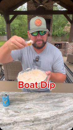 a man eating food from a bowl on top of a table with the caption boat dip