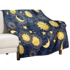 a couch with a blue and yellow blanket that has stars and moon designs on it