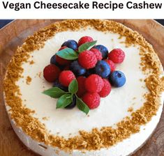 a cheesecake topped with berries and blueberries on top of a wooden cutting board