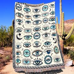 a blanket with an eye pattern on it in front of a cacti and cactus