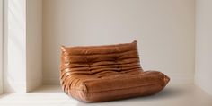 a brown leather chair sitting on top of a white floor in front of a window