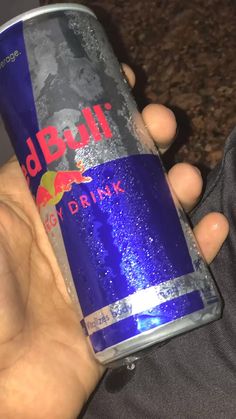 a person holding a can of red bull energy drink