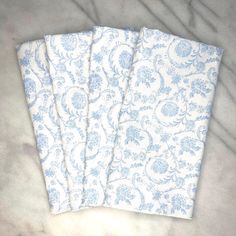 three pieces of blue and white fabric sitting on top of a marble countertop next to each other