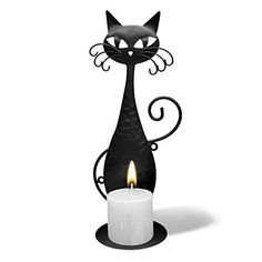 a black cat sitting on top of a candle holder with a lit candle in front of it