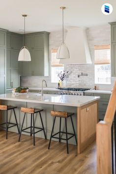 a kitchen with green cabinets and an island in the middle is seen from across the room