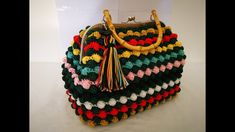 a multicolored crocheted purse with tassels on the handles and handle