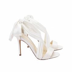 a pair of white high heeled shoes with bows on the toe and heels in satin fabric