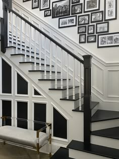 a staircase with pictures on the wall and a bench under it in front of some stairs