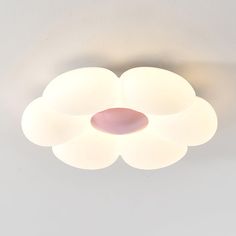 a white ceiling light with three lights on it's sides and a pink object in the middle