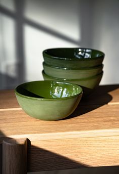 three green bowls sitting on top of a wooden table