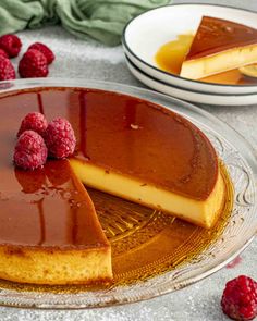 a chocolate cheesecake with raspberries is on a glass platter next to other desserts