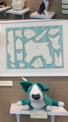 stuffed animals are sitting on display in front of a framed paper cut out of a dog