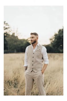 a man standing in a field with his hands on his hips wearing a vest and bow tie