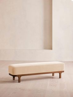 a bench sitting on top of a hard wood floor next to a white wall in an empty room