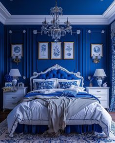 a blue and white bedroom with chandelier, bed, nightstands and pictures on the wall