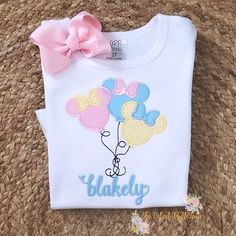 a white shirt with mickey mouse balloons on it and a pink bow in the front