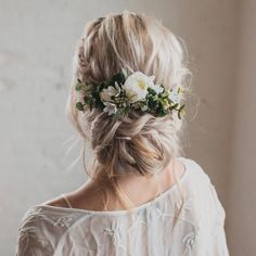 a woman with flowers in her hair wearing a white blouse and flower crown on her head