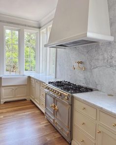 a kitchen with marble counter tops and gold trim on the oven, range hood, and windows