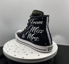 a black and white high top sneaker cake on a stand with pearls around the bottom