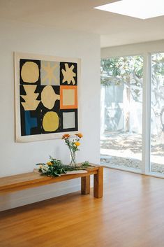 a wooden table sitting in front of a painting on the wall