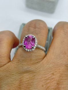 a woman's hand holding a pink diamond ring