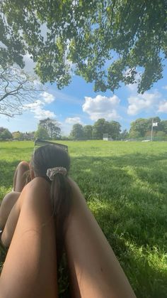 a woman laying in the grass with her back to the camera, looking at the sky