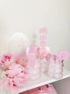 pink flowers are on the shelf next to some bottles and tags that say, one sunny day