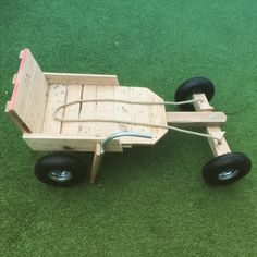 a wooden toy car with wheels on green grass