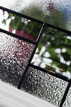 a close up of a glass window with trees in the background