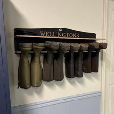 a row of boots hanging on a wall next to a door with the name wellingtons written on it