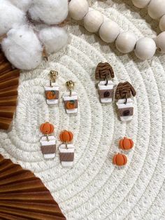 three pairs of earrings sitting on top of a white rug next to cotton balls and a wooden bead necklace