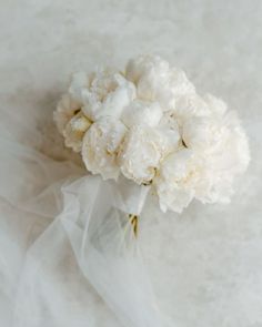 a bouquet of white flowers sitting on top of a white cloth covered tablecloth,