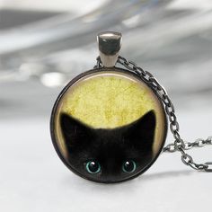 Handmade art pendant necklace featuring a peeking black kitten. You can choose your finish between antique bronze, antique silver, gunmetal or antique copper. This beautiful pendant is handcrafted by me... using a high quality art print image and is protected by a beautiful crystal clear domed glass cabochon which enhances the image for a truly stunning effect! The glass cabochon measures approximately 1 inch in diameter. The pendant and chain are nickel-free plated alloy and are available in an Black Cat Jewelry, Black Cat Necklace, Halloween Pendant, Cat Apparel, Cat Pendant Necklace, Black Kitty, Necklace Cute, Cat Fashion, Black Kitten