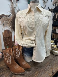 Scully Brand Pearl Snap Button Up Blouse Spread Collar Long Sleeves Two Faux Pockets On Chest Western Yokes Ivory Pearl Snap Front & Cuffs Ivory Cream Shirt Shiny Cream Embroidery 65% Poly 35% Rayon Fitted & Runs A Lil Small ~ Size Up If In Between Sizes Style PL-654 This Item Is Shipped To You From Our Manufacturer. Please allow 7-10 business days to receive it. Women's Sizing Recommendations XS 00/0 Small 2/4 Medium 6/8 Large 10/12 XL 14/16 XXL 18/20 ***These are shipped to you directly from o Cream Embroidery, Cowgirl Aesthetic, Rodeo Outfits, Cream Shirt, Ivory Pearl, Button Up Blouse, Snap Button, Dress To Impress, Button Up Shirts