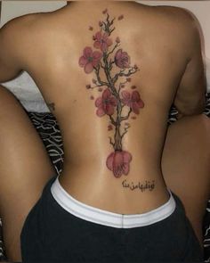 the back of a woman's tattoo with flowers on her lower and upper back