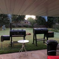 an outdoor grill area with two red chairs and a white table in the foreground