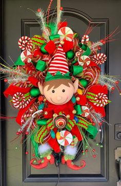 a christmas wreath with elfs and candy canes hanging on the front door,