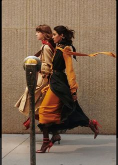 two women are walking down the sidewalk near a parking meter