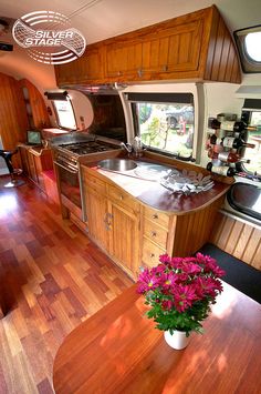 a kitchen and dining area in an rv with wood flooring, counter tops and cabinets