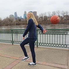 a woman is playing with a basketball near the water