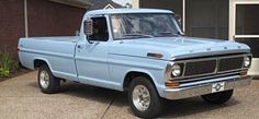 an old blue pickup truck parked in front of a house