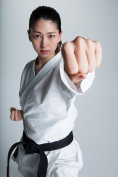 a woman in karate attire pointing at the camera