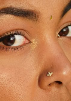 a close up of a woman's eye with gold piercings on her nose