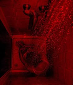 a bathroom with red light coming from the ceiling and water spraying over the toilet bowl