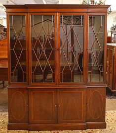 a wooden china cabinet with glass doors in a room filled with furniture and rugs