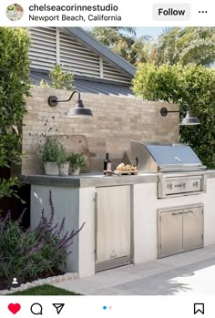 an outdoor kitchen with grill, sink and potted plants on the outside wall next to it