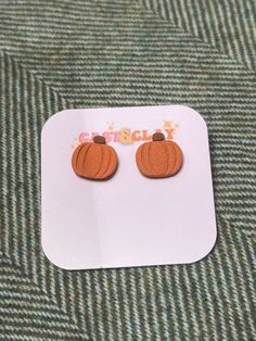 a pair of wooden pumpkin earrings sitting on top of a white plate