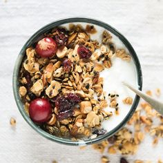 a bowl filled with granola and cherries on top of a table